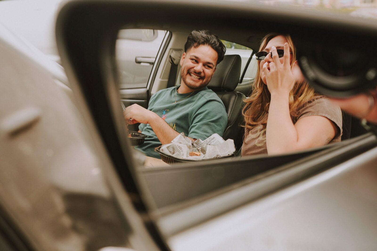 Couple laughing in a car, framed in the side mirror