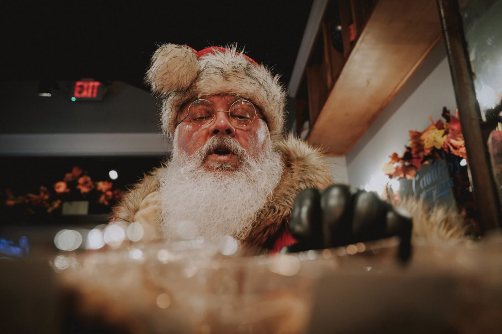 Santa leaning over a bar, lit by warm holiday light