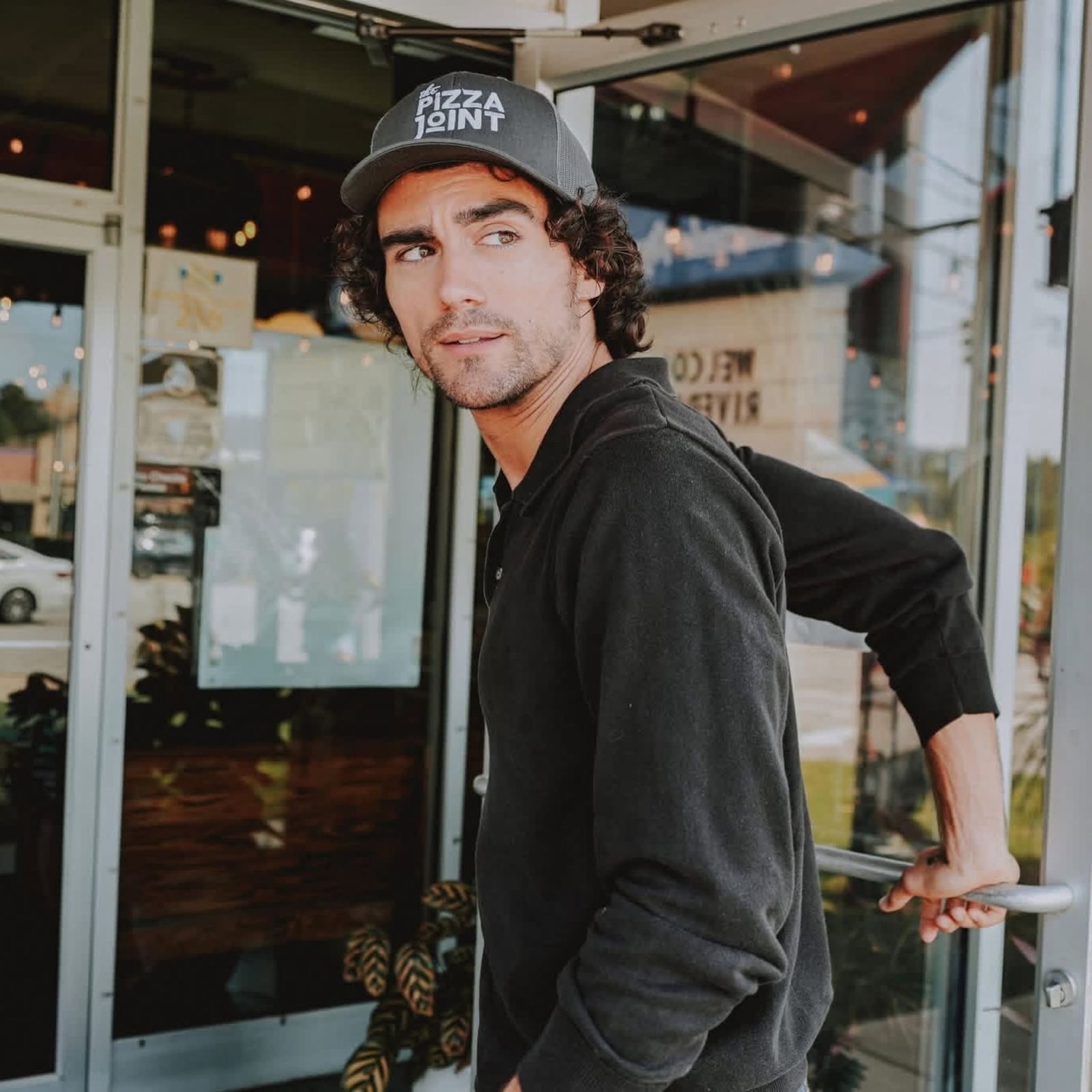 Man in a Pizza Joint cap stepping through the restaurant door